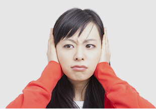 身穿紅色長袖T-shirt用雙手遮住耳朵的女性