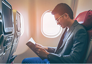 在機艙座位看書、穿西裝外套戴著眼鏡的外國男性乘客